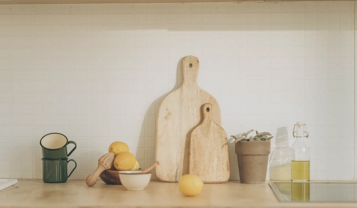 Warm kitchen scene featuring cutting boards, lemons, and cups on a wooden counter.