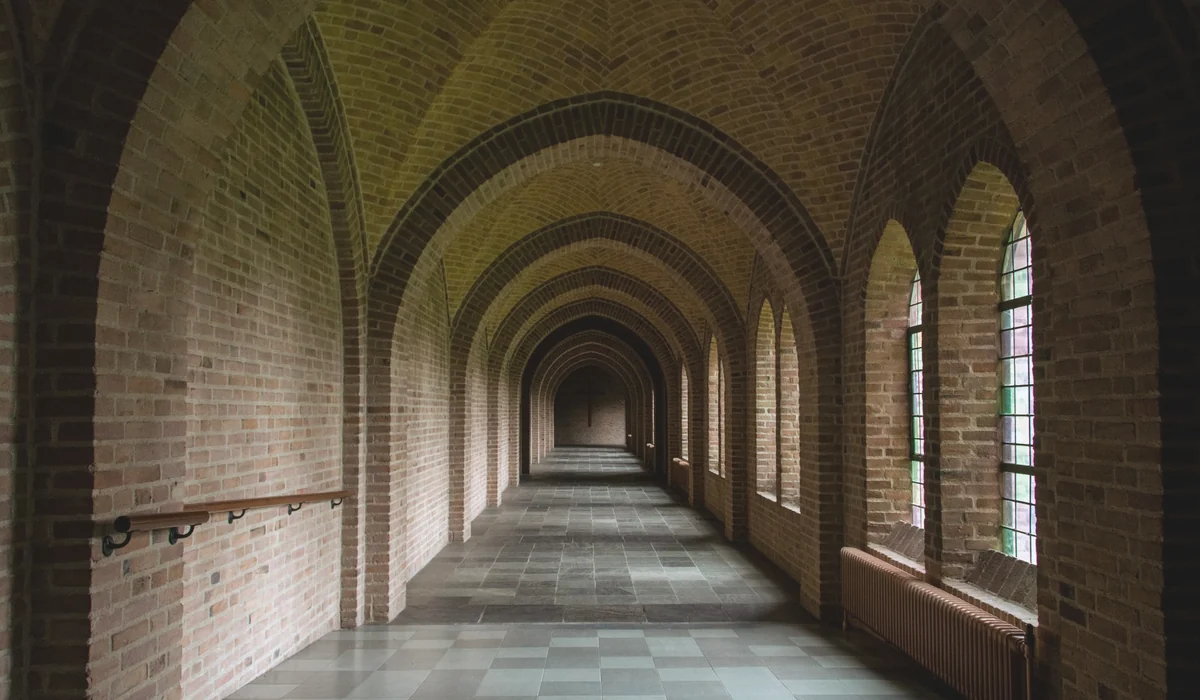 Explore the empty vintage corridor with arched brick ceilings and stained glass windows.