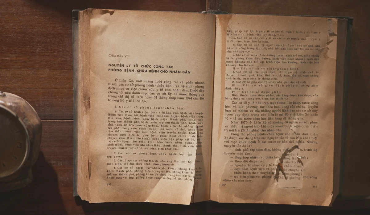 A vintage open book with text in Vietnamese on a wooden table, showcasing old literature.