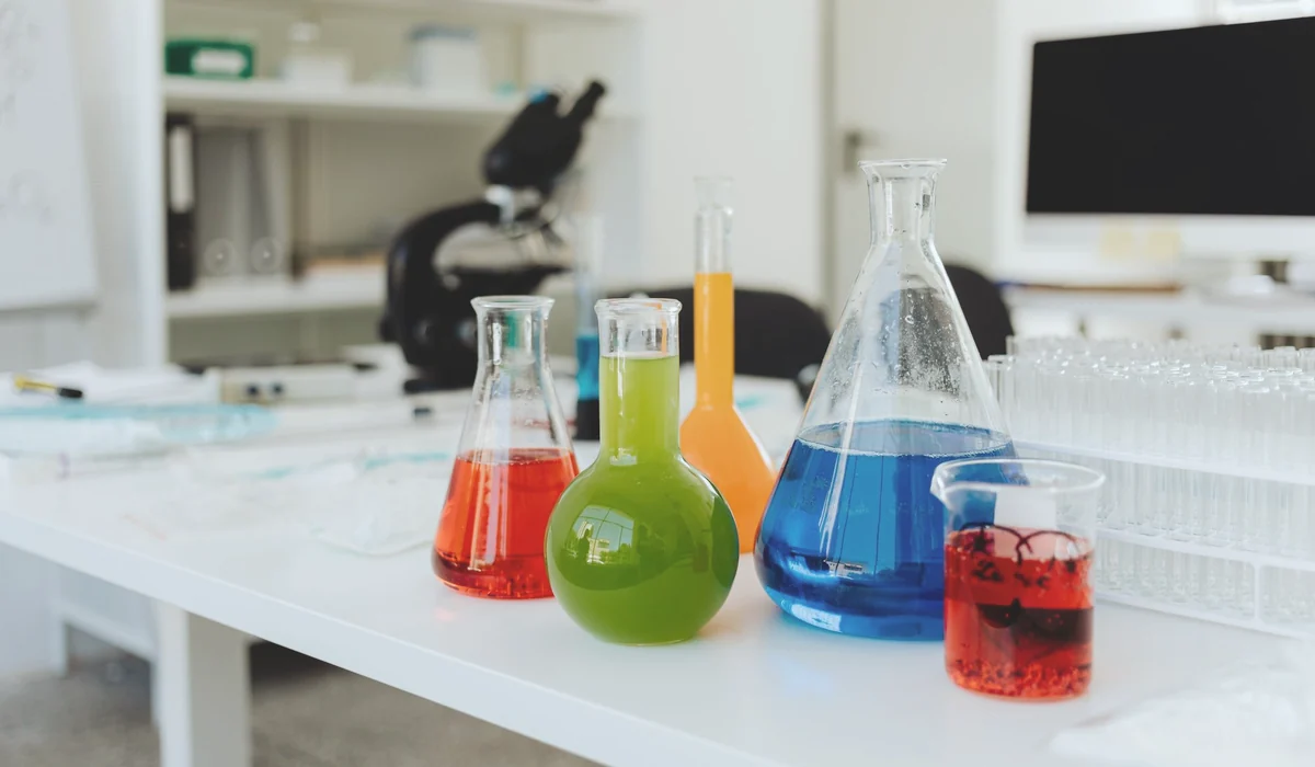 Bright, colorful chemicals in flasks and beakers on a lab table indicating a chemistry experiment in progress.
