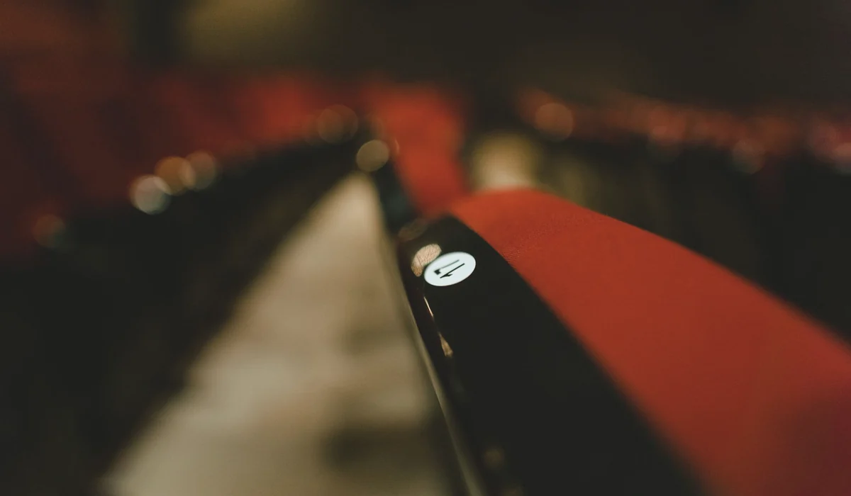 Blurred close-up of red theater seats in an empty auditorium highlighting seat number.