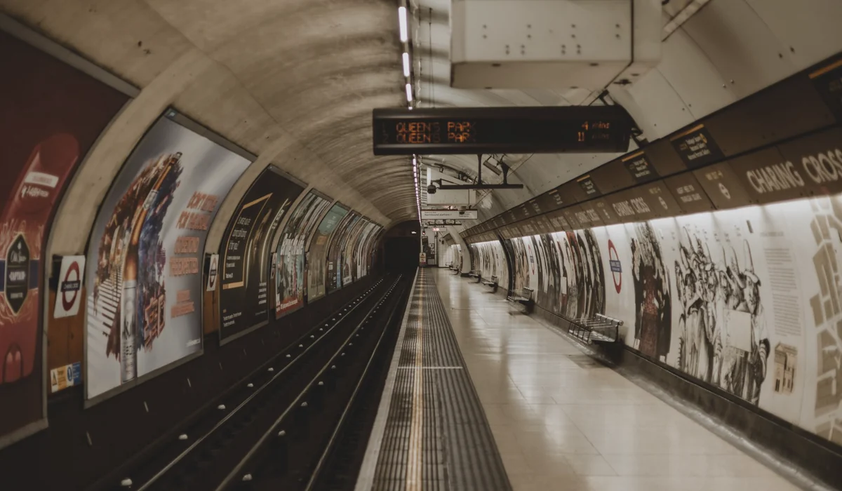 Empty London Underground tube station platform with signs and advertisements.